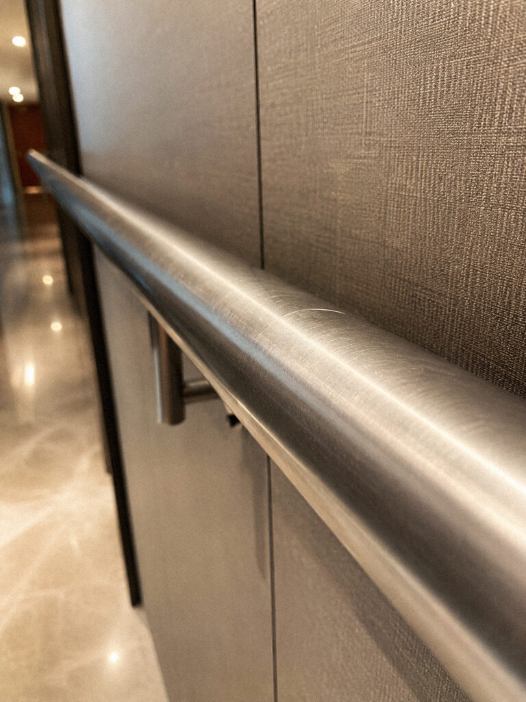 Acero inoxidable rayado en pasamanos de hotel, detalle de rayado superficial sobre acabado satinado